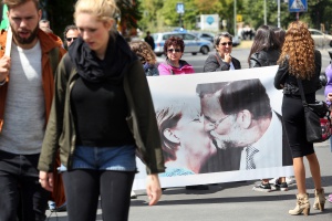 Protestors hold abanner depicting German chancellor Angela Merkel kissing Spanish Prime Minister Mariano Rajoy during a Blockupy demonstration in Berlin on June 20, 2015. Approximately 1,800 demonstrators marched for support of Greece amidst the country's economic crisis as well as for aid to refugees coming to Europe.   AFP PHOTO / ADAM BERRY