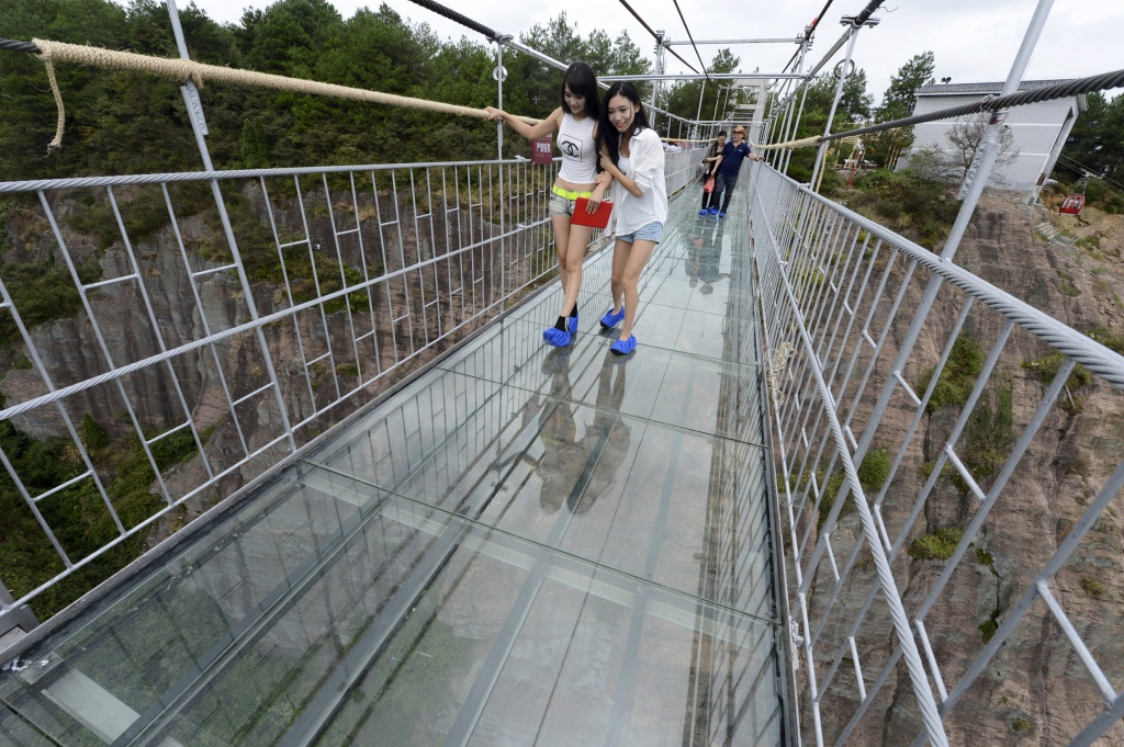 Tourists look down as they walk on a glass suspension bridge at the Shiniuzhai National Geo-park in Pinging county, Hunan province, China, September 24, 2015. The 300-metre-long (984 ft) glass bridge, which opened to tourists for the first time on Thursday, spans over a canyon which is about 180 metre deep (591 ft), local media reported. REUTERS/China Daily CHINA OUT. NO COMMERCIAL OR EDITORIAL SALES IN CHINA      TPX IMAGES OF THE DAY