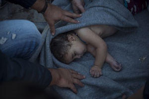 Paramedics and doctors care for a baby girl after a boat with refugees and migrants sunk while was crossing the Aegean sea from Turkey to the Greek island of Lesbos on Wednesday, Oct. 28, 2015. The condition of the child is not known. A 7-year-old boy died off Lesbos, where most migrants land, while a 12-month-old girl was in critical condition in hospital from the same boat accident. Greek authorities said Wednesday that at least five people, including four children, have drowned as thousands of refugees and economic migrants continued to head to the Aegean Sea islands in frail boats from Turkey, in worsening weather. (AP Photo/Santi Palacios)