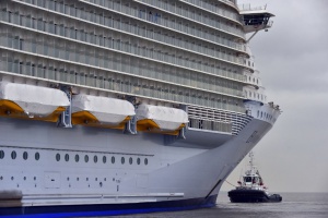 A tugboat leads the Harmony of the Seas cruise ship to leave the STX shipyard of Saint-Nazaire, western France, for a three-day offshore test, on March 10, 2016.  With a capacity of 6.296 passengers and 2.384 crew members, the Harmony of the Seas, built by STX France for the Royal Caribbean International, is the world's largest ship cruise.   / AFP / LOIC VENANCE