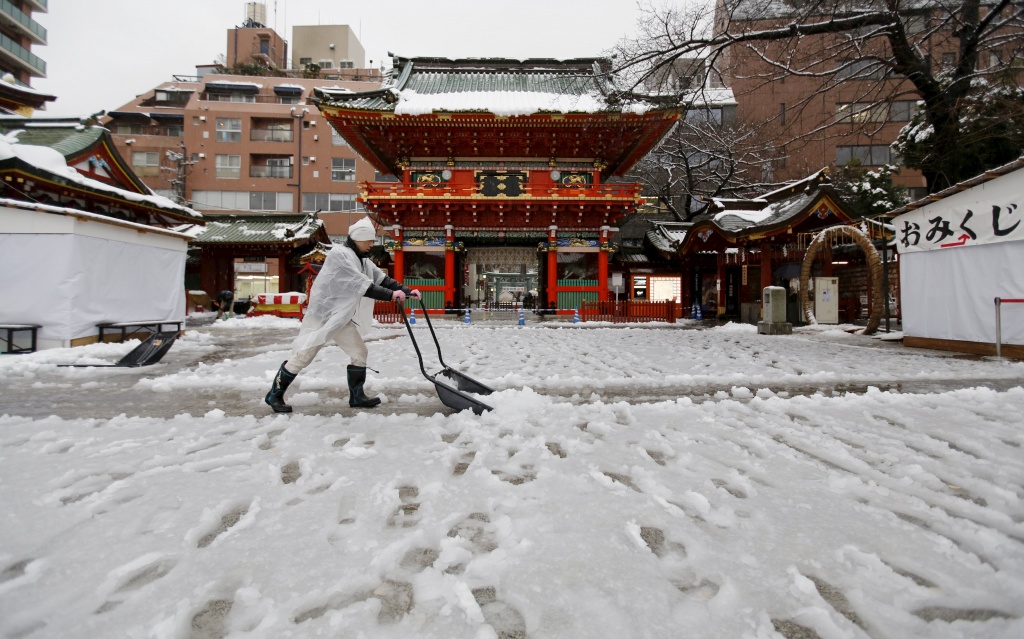 A man clears snow from a walkway at Kanda Miyojin Shrine in Tokyo, Japan January 18, 2016. REUTERS/Toru Hanai