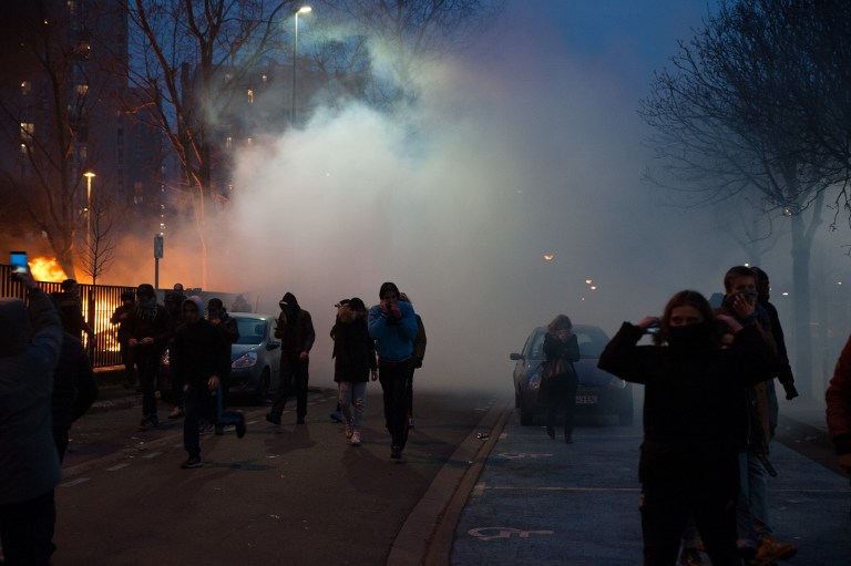 FRANCE, Bobigny: Protesters walk as smoke rises from a burning street during a protest in Bobigny, a district of northeast Paris, on February 11, 2017, to denounce police brutality after a black man was allegedly sodomised with a baton during an arrest while in custody earlier this month. One officer has been charged with rape and three others with assault over the incident in the tough northeastern suburb of Aulnay-sous-Bois which has revived past controversies over alleged police brutality. - Quentin Veuillet