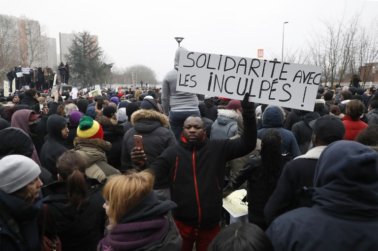 A placard is held that reads, "Solidarity with arrested protesters" as people rally in Bobigny to denounce police brutality after a black man was allegedly sodomised with a baton during an arrest while in their custody in Paris on February 11, 2017. A 22-year-old black youth worker named as Theo, no criminal record, required surgery after his arrest on February 2, 2017 when he claims a police officer sodomized him with his baton. One officer has been charged with rape and three others with assault over the incident in the tough northeastern suburb of Aulnay-sous-Bois which has revived past controversies over alleged police brutality. / AFP PHOTO / Patrick KOVARIK